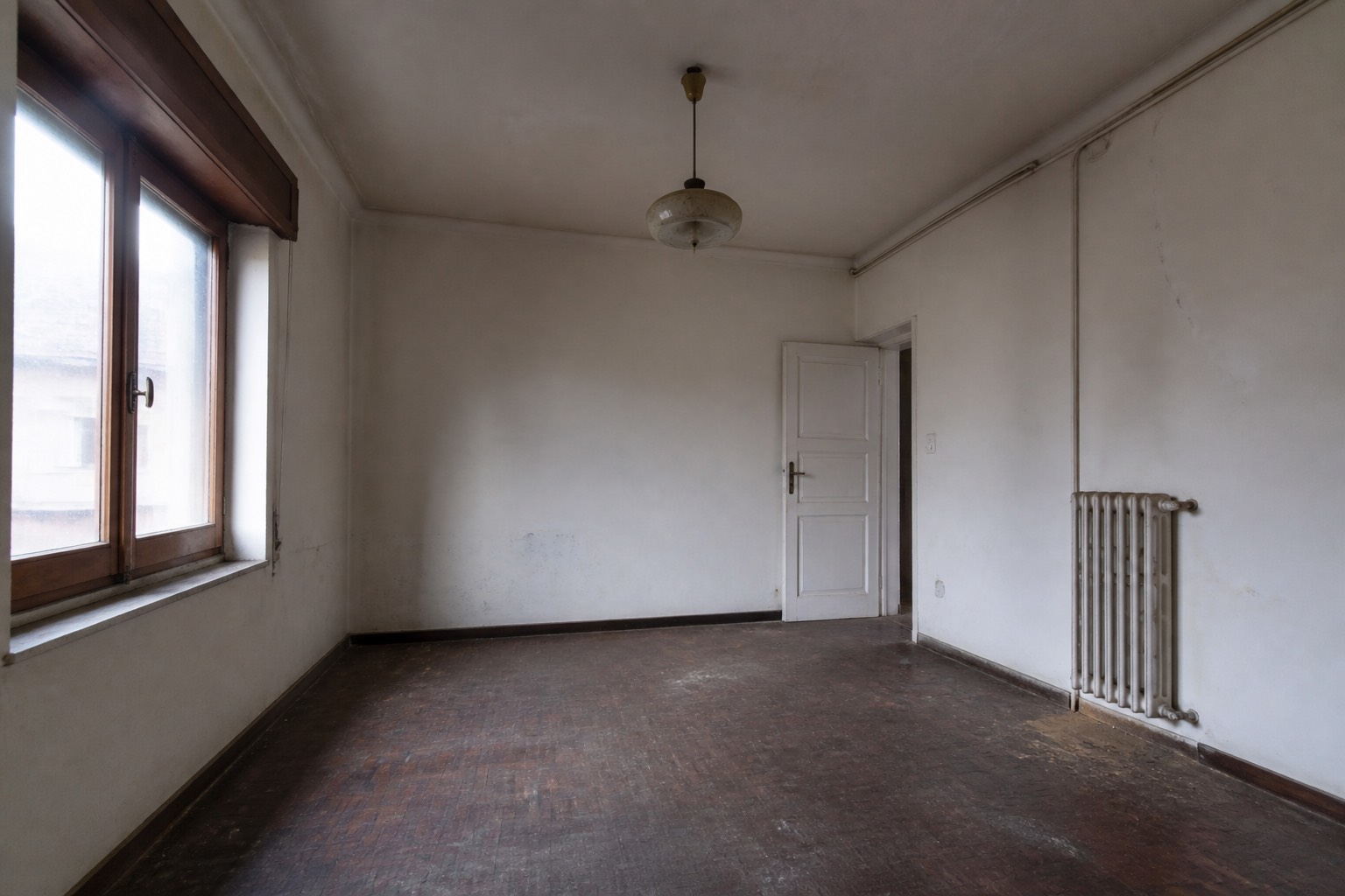 A mesma sala antes da obra, com paredes danificadas e piso velho / The same living room before the works, with damaged walls and an old floor
